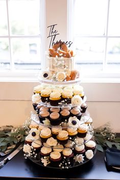 a tiered cake with cupcakes and flowers on it