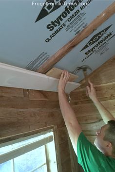 a man is working on the ceiling in his house with wood planks and white paint