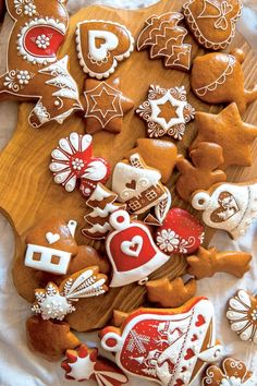 some very pretty decorated cookies on a wooden board with white cloth and decorations around them