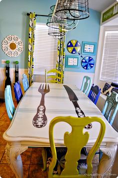 the dining room table is decorated with blue and yellow chairs, an iron birdcage hanging from the ceiling