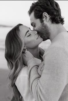 a man and woman kissing each other on the beach