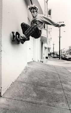 a young man riding a skateboard up the side of a building