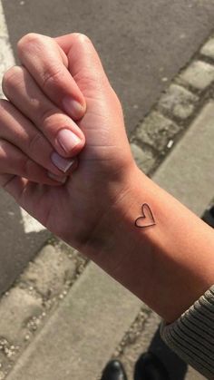 a woman's arm with a small heart tattoo on the left side of her wrist