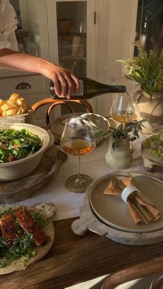 a person pouring wine into a bowl on top of a table filled with food and drinks