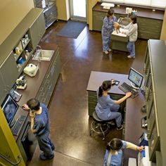 three people in scrubs are working on laptops at the same desk as two others