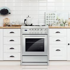 a stove top oven sitting inside of a kitchen next to white cabinets and counter tops