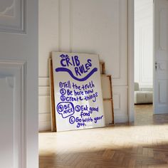 a sign on the floor in an empty room with white walls and parquet floors