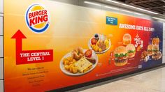 a subway station with a large advertisement on the wall for burger king and other fast food items