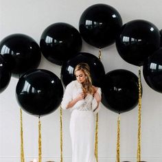 a woman standing in front of black balloons