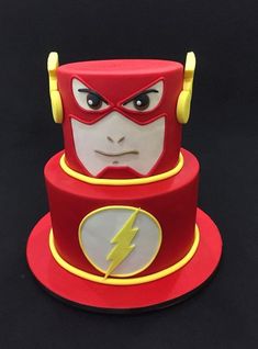 a red and yellow cake with the flash symbol on it's face is sitting on a black surface