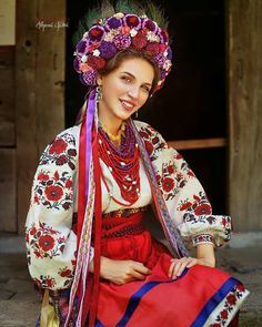 a woman in traditional dress sitting on the ground with her hand on her hip and smiling