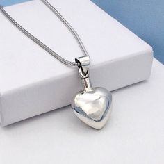 a silver heart pendant sitting on top of a white box