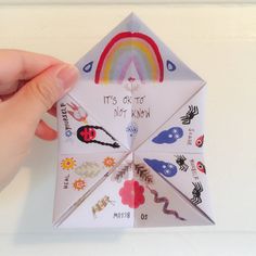 someone is holding an origami kite with stickers all over it's