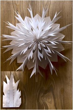 an origami flower on a wooden table next to a cut out piece of paper