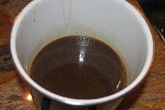 a white cup filled with liquid sitting on top of a counter