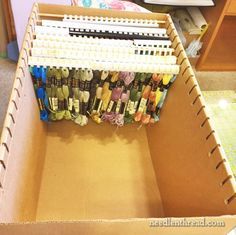 a cardboard box filled with lots of different colored clothes hanging from it's sides