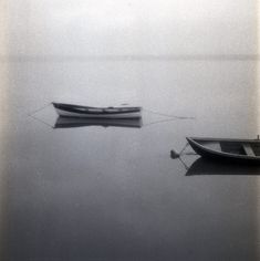 two boats floating on top of a body of water next to each other in the fog