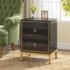 a black and gold side table with two drawers next to a green chair in a living room