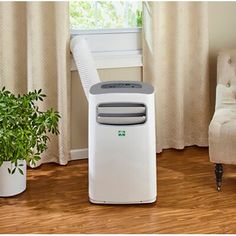 a white air conditioner sitting on top of a wooden floor next to a chair