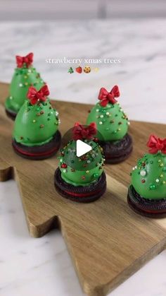 green cupcakes decorated with red bows and sprinkles on a wooden platter