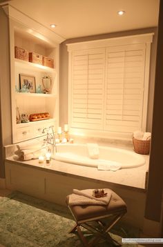 a white bath tub sitting in a bathroom next to a window with shutters on it