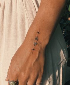 a woman's hand with a flower tattoo on her left wrist and two rings