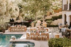 an outdoor dining area next to a pool with tables and chairs set up for dinner