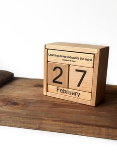 a wooden clock sitting on top of a table next to a piece of wood that says twenty seven