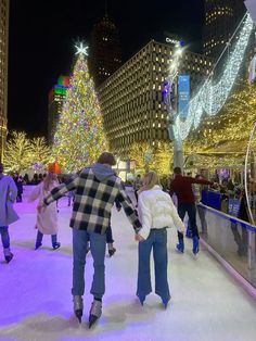 people skating on an ice rink at night with christmas lights in the city behind them