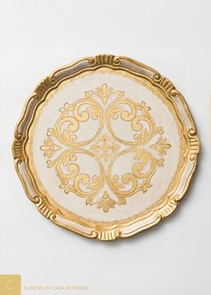 a gold and white plate with ornate designs on it's sides, against a white background