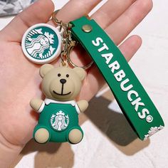 a hand holding a starbucks keychain with a teddy bear in the front and starbucks on the back