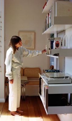 a woman standing in front of a stove top oven next to a wall mounted microwave