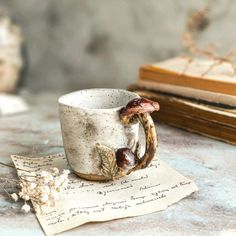 a coffee cup with a ring handle sitting on top of a piece of paper next to a book