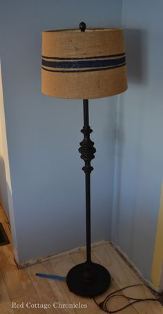 a lamp that is on top of a wooden floor next to a wall with a blue stripe around it