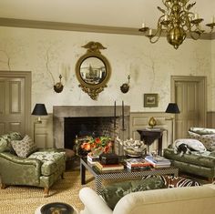 a living room filled with furniture and a fire place under a mirror on the wall