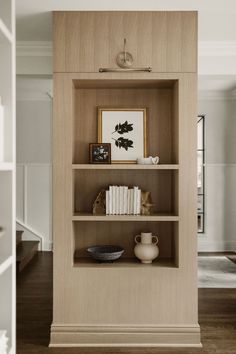 a book shelf with books and vases on it in the corner of a room