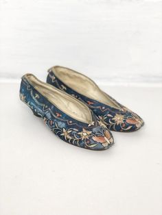 Chinese blue silk slippers from the 1800s, have allover hand floral embroidery, with butterflies at the toes. The shoes have a covered curved heel, and webbed binding around the top edge with a small silk tab at the back heel. The slippers are fully lined in a cotton, and are stamped on the inside ‘Made in China’ with a number. The shoes have leather soles.  ConditionStructurally good, with issues. The silk has worn down in areas - around the tow, on the sides, and on the back tab. The heels are Chinese Slippers, Silk Slippers, Historical Shoes, Historic Fashion, Chinese Blue, Antique Dress, Fashion Aesthetics, Blue Silk, Embroidered Silk