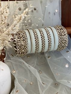 a stack of bracelets sitting on top of a table next to a vase filled with flowers