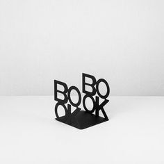 a black and white photo of the word boo book in cut out letters on a table