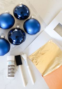 blue christmas ornaments are sitting on a table next to paintbrushes and other items