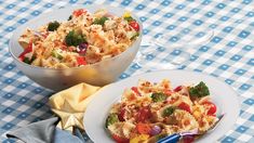 two bowls of food on a table with wine glasses and napkins next to them