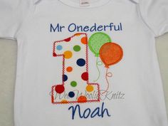 a white onesuit with the number one and balloons on it's chest, which reads, mr onederful noah