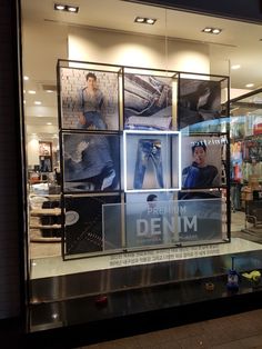 a window display with jeans and men's clothing in the front, behind which is an advertisement for denim