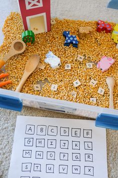 a plastic bin filled with food and wooden spoons next to a paper that says farm