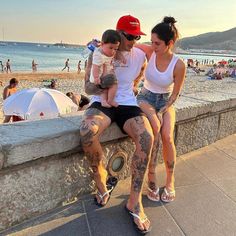 two women and a child are sitting on a wall at the beach