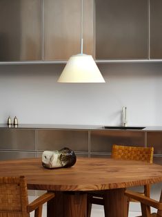 a wooden table with two chairs and a light hanging over it in a kitchen area