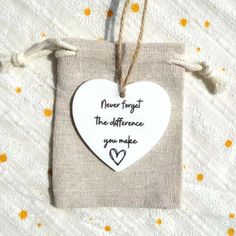 a white heart hanging from a string on top of a piece of paper with words