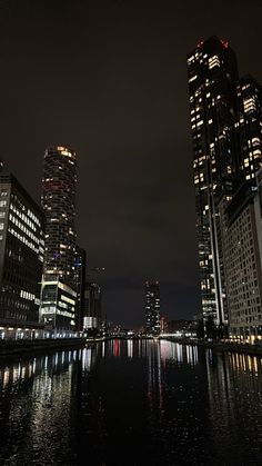 some very tall buildings by the water at night