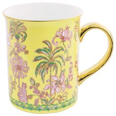 a yellow and pink coffee cup with floral designs on the outside, sitting in front of a white background