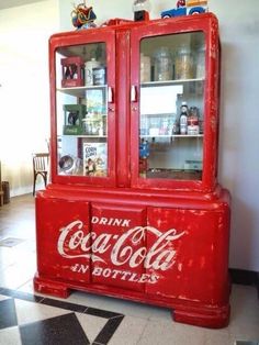 an old coca - cola cabinet is painted red and has two glass doors that are open